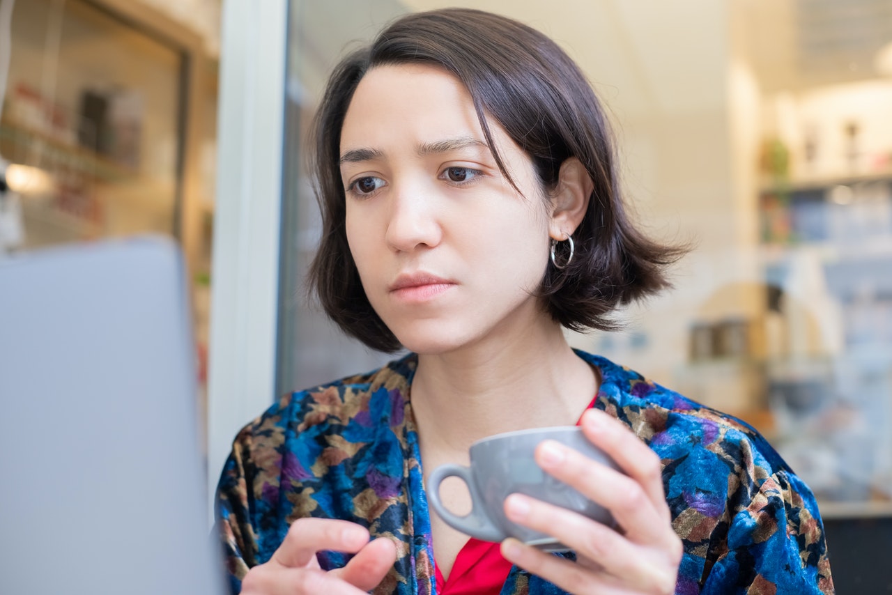 Woman drinking tea while working on her laptop